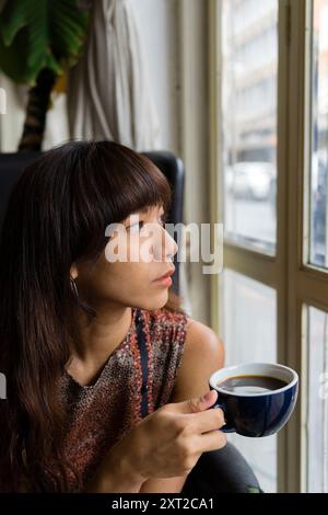 Jeune femme asiatique buvant du café chaud libéré Banque D'Images
