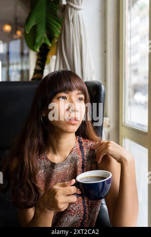 Jeune femme asiatique buvant du café chaud libéré Banque D'Images