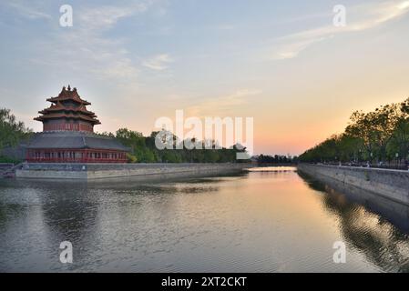 Tour nord-est de la Cité interdite se reflétant dans les douves d'eau lors du coucher du soleil à Pékin, capitale de la Chine, le 19 avril 2024 Banque D'Images