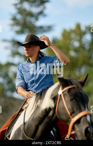 Un homme portant un chapeau de cow-boy et une chemise en denim bleu monte à cheval tout en regardant au loin. Bola03088 Copyright : xConnectxImagesx DATE D'ENREGISTREMENT PAS D'ÉTAT Banque D'Images