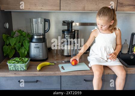 Petite fille préparant un jus sain ou un smoothie avec des fruits frais dans la cuisine à la maison Banque D'Images