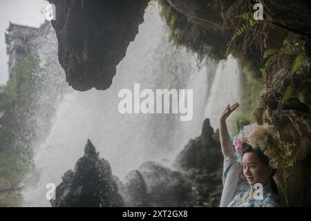 Femme en tenue traditionnelle posant près d'une cascade entourée de formations rocheuses naturelles et de brume à Fu Rong, Hunan, Chine Banque D'Images