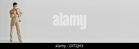 Une femme en costume beige pose devant un fond blanc. Banque D'Images