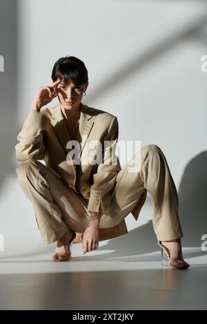 Une femme portant un costume beige pose dans un cadre de studio. Banque D'Images