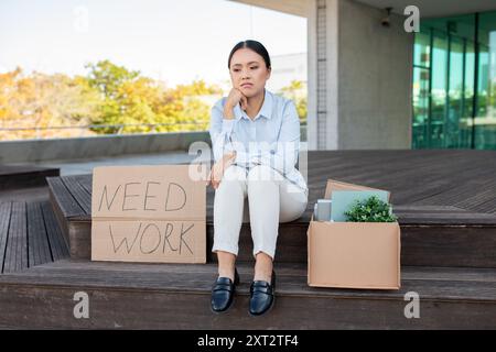 Jeune femme assise sur les marches avec le signe de travail nécessaire Banque D'Images