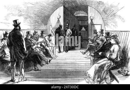 Le métro de la Tamise à Tower-Hill : salle d'attente, 1870. Tunnel sous la Tamise à Londres, conçu par William Henry Barlow. Le métro [de Tower-Hill à Tooley-Street, Southwark] se compose d'un tunnel étroit réunissant deux puits verticaux... les puits à chaque extrémité du tunnel sont de 60 pieds. En profondeur... dans les puits se trouvent des ascenseurs, transportant six passagers à la fois, et ces ascenseurs sont levés et abaissés par les mêmes moteurs qui font fonctionner les tambours… en arrivant au fond [les passagers] trouvent un espace de quelques pieds entre le puits et les tampons équipés de bancs, comme une salle d'attente. Lorsque le o Banque D'Images