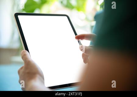 Personne tenant une tablette avec un écran vierge, dans un environnement vert lumineux. Image parfaite pour présenter des applications de tablette, des interfaces utilisateur ou des graphiques Banque D'Images