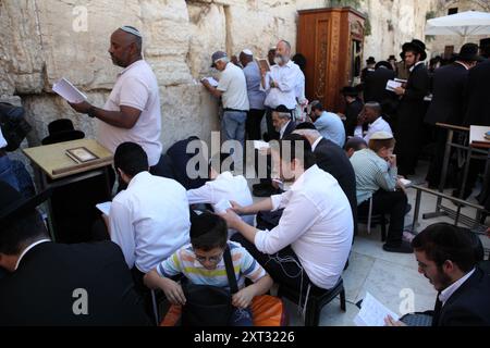 Tisha B'AV, les Juifs sont assis sur des couchettes ou debout au mur occidental, pleurent la destruction du Temple et lisent des lamentations, certains sont pieds nus ou portent des chaussures en caoutchouc Banque D'Images