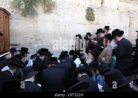 Tisha B'AV, les Juifs sont assis sur des couchettes ou debout au mur occidental, pleurent la destruction du Temple et lisent des lamentations, certains sont pieds nus ou portent des chaussures en caoutchouc Banque D'Images