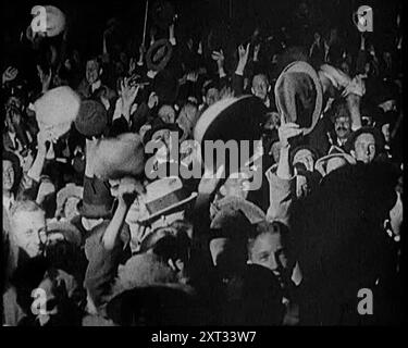 Crowds Cheering à Trafalgar Square, Londres, 1922. «Les conservateurs ont gagné la journée, et la coalition a été déclarée bien et vraiment morte, et la foule à Londres l'a emporté le soir des élections, alors que Bonar Law et son cabinet déménageaient au 10 Downing Street». De "Time to Remember - Sitting Still and Going Slowly", 1922 (Reel 2) ; revue des événements de 1922, y compris les troubles irlandais, la guerre entre la Grèce et la Turquie et les développements dans l'aviation et la radio. Banque D'Images