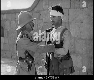 Scène tirée d'un film : acteur masculin jouant un survivant de la bataille interrogé. Sa tête est en bandages et il porte un baïonnette, années 1920 'Le fort d'Umballa [Ambala], au-dessus duquel le drapeau flottait encore, oh eh bien, le nom du film n'a pas d'importance, mais une charge courageuse a bientôt mis cette situation en valeur, marchant dans la forteresse soulagée, seulement pour trouver, au milieu des tristes, juste un défenseur vivant, et celui-là, juste'. De "Time to Remember - came the Dawn", 1925 (Reel 3) ; aperçu de l'industrie cinématographique britannique des années 1920 - extraits de grands films muets et de nouvelles. Banque D'Images