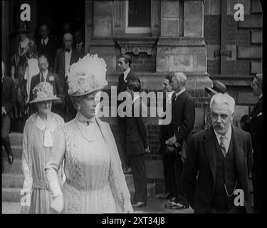 La reine Mary et le roi George V accompagnés d'un groupe de fonctionnaires sortant d'un édifice , 1924. De "Time to Remember - A Trip to Europe", 1924 (bobine 2) ; un regard sur la vie politique et sociale en Europe et au-delà en 1924. Banque D'Images