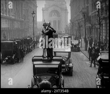 Un couple dansant le Charleston sur le dessus d'une voiture conduisant dans une rue de Londres, 1926. De "Time to Remember 1926 - Short Sharp Shower" ( Reel 4) ; documentaire sur 1926 - grève générale, politique internationale, danse, météo et exploits record. Banque D'Images