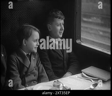 Deux enfants de sexe masculin dans un chariot de train assis devant une table posée pour un repas, 1931. 'Avez-vous déjà pris les numéros de moteur ? Avez-vous déjà ressenti le frisson de vous retrouver dans un train aussi crack que le Flying Scotsman ? » De "Time to Remember - A New Era", 1931 (bobine 3) ; documentaire sur le monde au début des années 1930 Banque D'Images