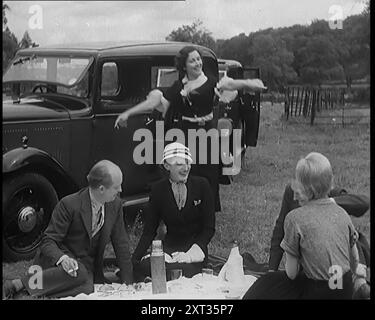 Civils hommes et femmes pique-niquant à côté d'une voiture, 1931. « S'éloigner de tout cela était... une autre caractéristique de l'époque. En voiture, en pédalant ou à pied, les masses cherchaient l'air frais, comme si cela aussi était quelque chose qui venait d'être inventé. De "Time to Remember - A New Era", 1931 (Reel 2) ; documentaire sur le monde au début des années 1930 Banque D'Images