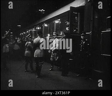 Benito Mussolini, le leader italien, debout sur une plate-forme avec le roi Victor Emmanuel III, roi d'Italie, et Galeazzo Ciano attendant de saluer Adolf Hitler, le leader allemand, alors qu'il quitte un train à la gare d'Ostiense à Rome, 1938. De "Time to Remember - Wind Up week", 1938 (Reel 2) ; film documentaire sur 1938 - les gens prennent conscience de la menace croissante de la guerre. Banque D'Images