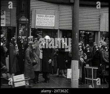 Hommes et femmes attendant sur un trottoir portant des masques à gaz, 1939. De "Time to Remember - The Reluctant Warriors", 1939 ( Reel 3) ; documentaire sur les événements de 1939 - les préparatifs pour la guerre et les hostilités éclatent. Banque D'Images