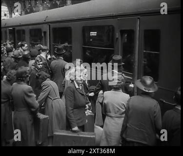 Passagers masculins et féminins, certains tenant des valises, sur une plate-forme d'une grande gare en attente d'embarquement dans des voitures, 1938. De "Time to Remember - Wind Up week", 1938 (Reel 2) ; film documentaire sur 1938 - les gens prennent conscience de la menace croissante de la guerre. Banque D'Images