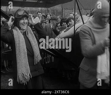 Civil masculin et civil féminin debout devant un avion portant un chapeau d'aviateur surveillé par d'autres civils, 1927. Un couple nouvellement marié se préparant à s'envoler pour leur lune de miel dans leur avion biplace Westland Wigeon. De "Time to Remember - Fast and Far in the Twenties", 1927 (bobine 1) ; un regard sur l'obsession de la vitesse et du voyage à la fin des années 1920 Banque D'Images