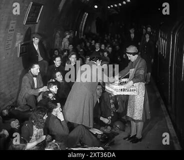 Des rafraîchissements sont servis aux civils tout en s'abritant des bombes dans le métro de Londres, 1940. La Grande-Bretagne pendant la seconde Guerre mondiale : des civils à l'abri du Blitz de Londres. « Au-dessous de la plus grande ville du monde, un hôte s'installe pour dormir, au plus profond de la nuit effrayante [par exemple, les bombardements allemands]. Burrows pour les êtres humains loin des bombes et une pluie d'acier des armes bien intentionnées [ie britannique]. N'est-ce pas le plateau à thé qui arrive ? ». De "Time to Remember - Standing Alone", 1940 (bobine 4) ; film documentaire sur les événements des derniers mois de 1940. Banque D'Images