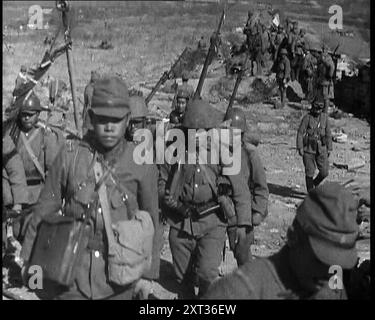 Soldats japonais masculins avec des fusils marchant jusqu'à une colline, près de la ville de Hankow, 1937. Invasion japonaise de la Chine. Avant la ville de Hankow, les Japonais tonnaient dans les anciennes fortifications. Le passé descend devant une conception nouvelle et terrible de l'avenir. La conception de la puissance étant juste, et la Terre sera héritée par les forts... avec la chute de Hankow, les conquérants rendent hommage aux croyances qui les ont conduits à ses guerres. De "Time to Remember - Sense of Values", 1937 (bobine 4) ; film documentaire sur les événements de 1937, la guerre en extrême-Orient, construire à la guerre Banque D'Images