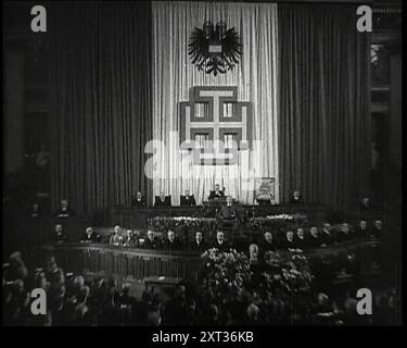 La salle de débat du Parlement à Vienne pendant l'annexion nazie allemande de l'Autriche, avec des politiciens remplissant la salle en écoutant Kurt Schusschnigg, le chancelier autrichien, au Lectern et les hauts fonctionnaires sur le Dais derrière lesquels se trouvent des rideaux dans le rouge et blanc du drapeau autrichien sur lesquels sont montés un symbole d'aigle à double tête et la croix le Parti 'Front patrie', 1938. De "Time to Remember - Wind Up week", 1938 (bobine 1) ; film documentaire sur 1938 - les gens prennent conscience de la menace croissante de la guerre. Banque D'Images