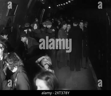 Civils à l'abri des bombes dans le métro de Londres, 1940. La Grande-Bretagne pendant la seconde Guerre mondiale : des civils à l'abri du Blitz de Londres. « Au-dessous de la plus grande ville du monde, un hôte s'installe pour dormir, au plus profond de la nuit effrayante [par exemple, les bombardements allemands]. Des terriers pour les êtres humains loin des bombes. De "Time to Remember - Standing Alone", 1940 (bobine 4) ; film documentaire sur les événements des derniers mois de 1940. Banque D'Images