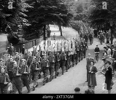 Volontaires britanniques de la Défense locale marchant à Parade, 1940. Seconde Guerre mondiale. Ils ont commencé comme volontaires de la défense locale. Leurs âges combinés totalisaient probablement plus que toute l'histoire de l'île qu'ils étaient prêts à défendre. Bientôt, ils devaient être appelés la Garde intérieure, et atteindre une force d'un million et demi d'hommes. Mais en cet été de 1940, ils n'avaient ni la force, ni les armes appropriées. Seulement une résolution : mourir, si besoin est, et dans leur mort, d'en prendre au moins un avec eux. Et beaucoup de jeux qu'ils avaient joués à la guerre sous la menace de la vraie chose... petite question qui serait dans Banque D'Images