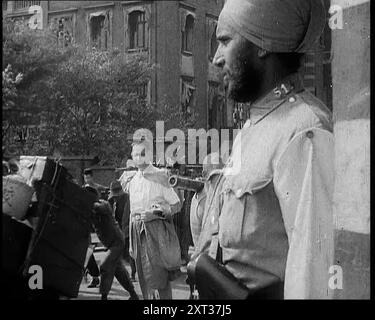 Soldat indien dans le règlement international de Shanghai avec un civil regardant, 1937. '...parmi les étrangers à Shanghai se trouvaient ceux qui avaient de plus grandes ambitions que le simple commerce. Dans leurs petites îles serrées et surpeuplées, les Japonais chérissaient un sens des valeurs qui leur est propre. Alors que le Japon émergeait de sa longue réclusion dans le monde moderne, ses dirigeants, inspirés par les vieilles traditions qui suppliaient tous de mourir pour l'honneur de leur pays, cherchaient l'expansion et la conquête. Le monde occidental leur avait donné le cuirassé, le canon, la bombe. Maintenant, ils ont cherché la chance de les utiliser à bon escient. Banque D'Images