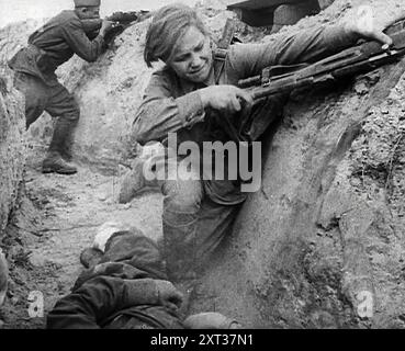 Deux soldats russes se cachant dans une tranchée, 1941. Seconde Guerre mondiale. L'opération Barbarossa était l'invasion de l'Union soviétique par l'Allemagne nazie. '...dans les villages censés être soumis, le long des lignes d'approvisionnement vitales, les attaques foudroyantes des partisans...Un ours mort non seulement refusant de s'allonger, mais utilisant en fait ses griffes. Dans son agonie, la Russie sous Staline, comme la Russie autrefois sous Alexandre, a retrouvé le courage passionné d'un peuple qui aimait sa terre ». De "Time to Remember - Operation Barbarossa", 1941 (bobine 3) ; film documentaire sur les événements de 1941, sur le front de l'est et à Pea Banque D'Images