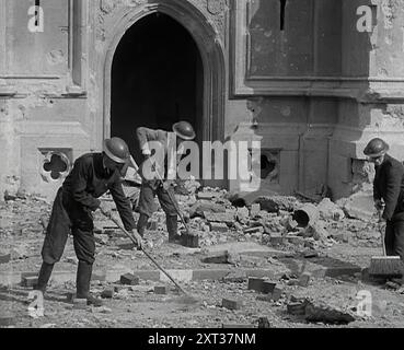 Les gardes britanniques du RAID aérien nettoyent les décombres autour du palais de Westminster, Londres, 1941. Seconde Guerre mondiale. 'La Grande-Bretagne... savait tout sur la guerre avec l'Allemagne nazie. À présent, elle était très habituée aux tags "business as usual", à l'improvisation, au making-do dans la rue". De "Time to Remember - Operation Barbarossa", 1941 (bobine 1) ; film documentaire sur les événements de 1941, sur le front de l'est et à Pearl Harbour. Banque D'Images