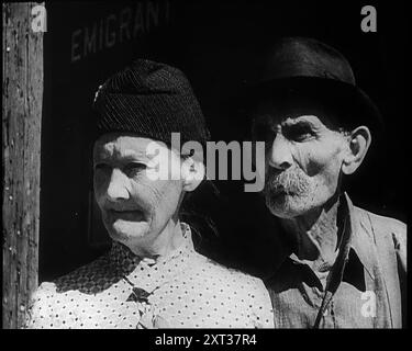 Visages d'un couple âgé alors qu'ils regardent un train arriver à une gare, 1932. Les États-Unis pendant la Grande dépression. De "Time to Remember - Around the Corner", 1932 (bobine 1) ; journal des événements de 1932 aux États-Unis d'Amérique - Franklin Roosevelt devient le président. Banque D'Images