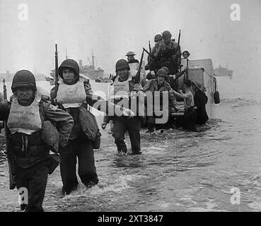 Troupes américaines marchant sur une plage nord-africaine dans le cadre de l'opération Torch, 1942. Seconde Guerre mondiale. Une grande armada se déplace sur les eaux de l'Atlantique. Navire après navire, entassé de troupes, britanniques et américaines - l'opération Torch a été allumée. Là balaie à terre une force en Afrique du Nord - une force destinée à attraper Rommel en retraite comme si dans un vice, et destinée ensuite à détruire son Afrika Korps' vantée. De "Time to Remember - The End of the Beginning", 1942 (bobine 4) ; film documentaire sur les événements de 1942 et l'entrée de l'Amérique dans la guerre. Banque D'Images