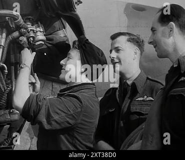 Personnes inspectant une partie d'un avion, 1942. La Grande-Bretagne pendant la seconde Guerre mondiale. "...la fille qui fait la chose qui tient l'huile qui huilent la bague qui conduit la tige qui déplace la manivelle qui fonctionne la chose-ummy-bob. C'est une sorte de boulot chatouilleux faire une chose pour un truc-ummy-bob, surtout quand on ne sait pas à quoi ça sert. Mais c'est la fille qui fait la chose qui perce le trou qui tient l'anneau qui fait la chose-ummy-bob qui fait rugir les moteurs". Paroles de "The Thing-ummy-Bob [That's Going to Win the War]", une chanson célébrant le produit féminin Banque D'Images