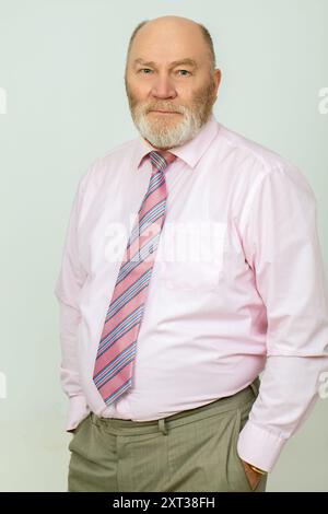 Portrait d'un homme âgé aux cheveux gris avec une barbe portant une chemise rose et une cravate. Banque D'Images