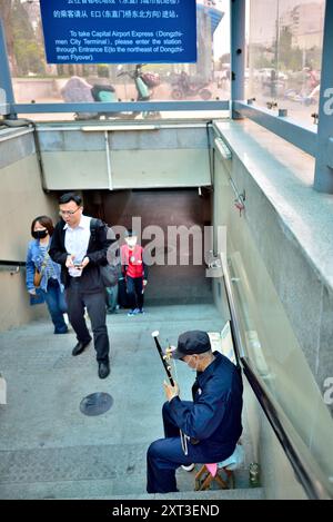 Homme âgé jouant d'un instrument traditionnel chinois à l'entrée de la station de métro Dongzhimen à Pékin, capitale de la Chine, le 22 avril 2024 Banque D'Images