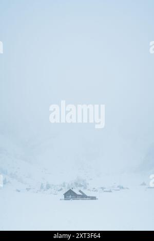 Une scène suisse sereine avec une maison solitaire embrassée par un paysage enneigé, évoquant un sentiment de calme et d'isolement au milieu d'une merveille hivernale Banque D'Images