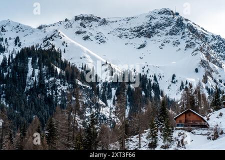 Une scène hivernale sereine dans les Alpes suisses avec une maison rustique au milieu des montagnes enneigées et des pins, mettant en valeur le bea hivernal à couper le souffle de la Suisse Banque D'Images