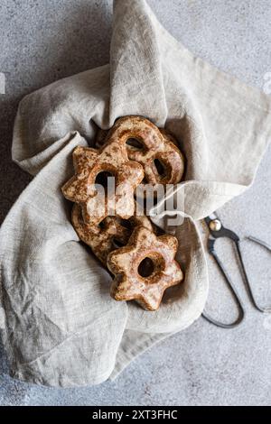 D’en haut, des biscuits en pain d’épices faits maison en forme d’étoiles sont nichés dans un tissu de lin naturel, évoquant une ambiance cosy et rustique. Les biscuits sont poussiéreux Banque D'Images