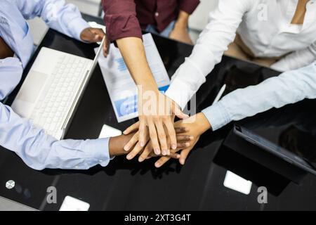 Cette image capture une équipe diversifiée d'éducateurs de l'académie anglaise avec leurs mains ensemble, symbolisant la collaboration et l'unité qu'ils sont autour d'une table Banque D'Images