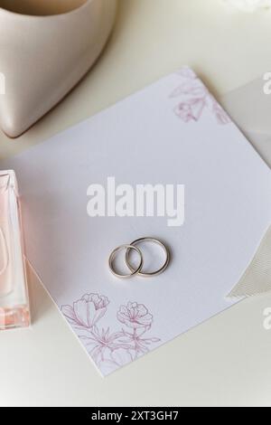 Essentiels de mariage de la mariée : talons, bouquet, bagues, parfum, et invitation sur une table blanche Banque D'Images