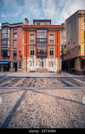 Des bâtiments colorés bordent les rues pavées sous un ciel bleu dans la ville historique de Gijon, en Espagne, mettant en valeur le charme urbain européen. Banque D'Images