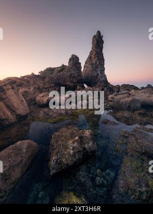 Une vue spectaculaire sur les formations rocheuses escarpées s'élevant au-dessus des marées, capturée au coucher du soleil sur la côte nord des Asturies, mettant en valeur l'art de la nature A. Banque D'Images