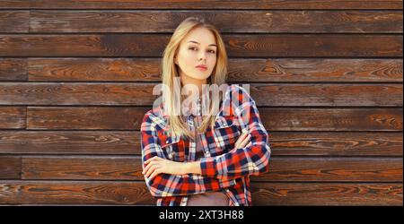 Portrait de belle jeune femme blonde caucasienne confiante avec les bras croisés dans une chemise à carreaux décontractée dans la ville Banque D'Images