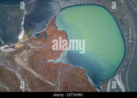 Captivante photo par drone d'un lac serein des hautes terres en Islande, mettant en valeur un plan d'eau turquoise unique entouré de paysages accidentés et de sho texturés Banque D'Images