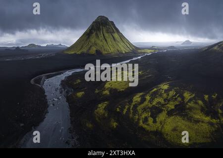 Vue aérienne spectaculaire de Maelifell, un volcan vert aux formes distinctives dans les hautes terres désolées d'Islande, entouré de sols volcaniques sombres et d'hivers Banque D'Images