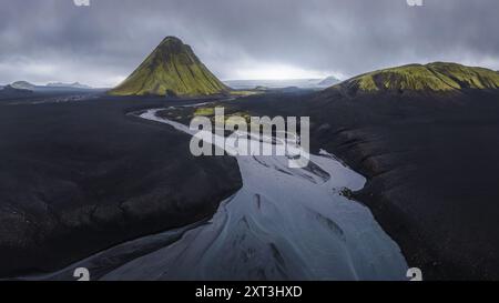 Vue aérienne du volcan Maelifell frappant entouré de sables volcaniques sombres contrastant avec une rivière argentée sinueuse dans les hautes terres reculées d'Icela Banque D'Images