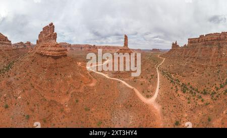 Une photo aérienne panoramique capture un paysage orange avec des formations rocheuses emblématiques et une route de terre sinueuse dans la Vallée des Dieux de l'Utah Banque D'Images