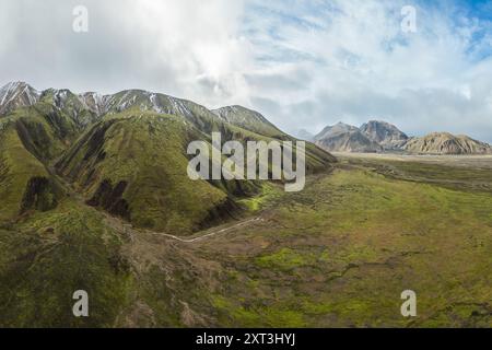 Vue aérienne des montagnes verdoyantes contrastant avec les montagnes enneigées de Green Highlands, Islande, montrant la splendeur de la nature et de la Banque D'Images