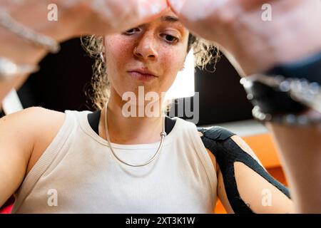 Cette image en gros plan montre une jeune femme intensément concentrée alors qu'elle se prépare à un exercice d'haltérophilie, son dévouement et sa concentration soulignent Banque D'Images